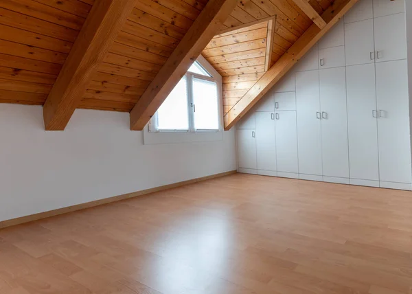 Interior view chalet style room with parquet flooring and wooden beam roof and wall to wall closet — 스톡 사진