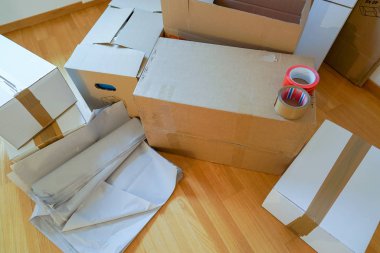 close up view of moving boxes and materials on a wooden parquet floor