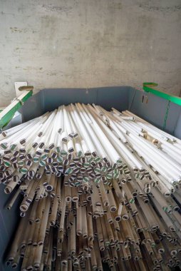 selective focus view of large recycling bin filled with stacks of long tubular light bulbs