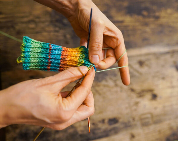 close up of female hands knitting colorful socks