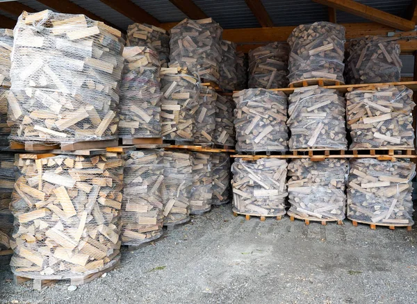 Gewikkelde bundels van voorgesneden brandhout op pallets of skids, gereed voor verkoop en verzending — Stockfoto