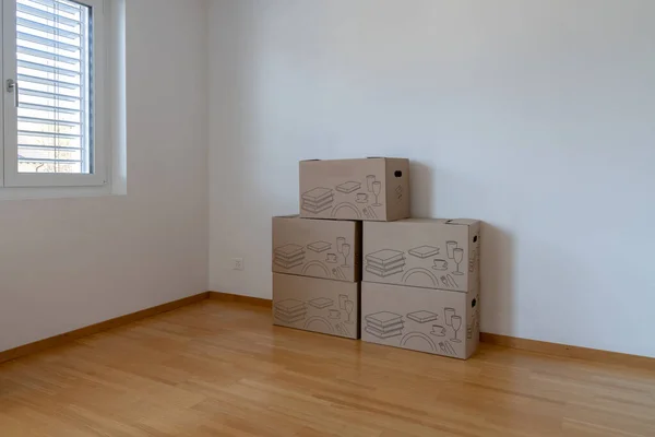 Horizontal view of large brown moving and packing boxes in an empty apartment room