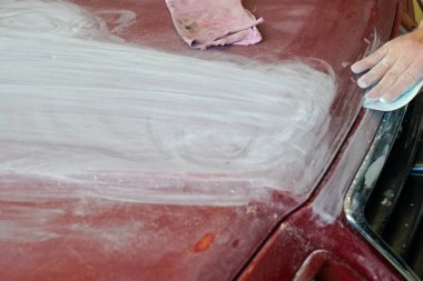 Boya yapmadan önce bir adamın el kaputunu zımparalarken yakın çekim görüntüsü.