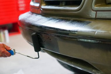 Ordu cipini boyayan ve siyah süslemeler yapan bir adamın yakın çekimi.