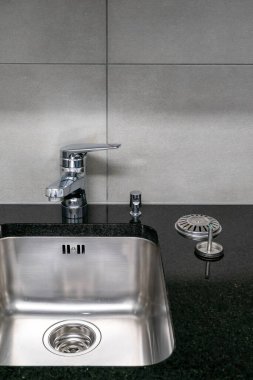 Çok temiz bir mutfak lavabosu, musluğu ve siyah kuvars taşı atölyesinin lazer ve lavabo tıkanıklığıyla yakın plan.