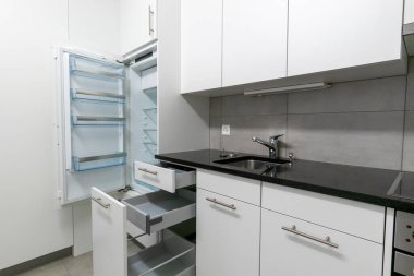 Gri beyaz ve siyah taştan yapılmış basit ve modern bir mutfak manzarası.