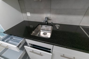 Gri beyaz ve siyah taştan yapılmış basit ve modern bir mutfak manzarası.