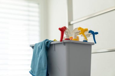 Alüminyum iskele üzerindeki pencereleri temizlemek için sprey şişeleri ve kumaşları olan gri bir kova.