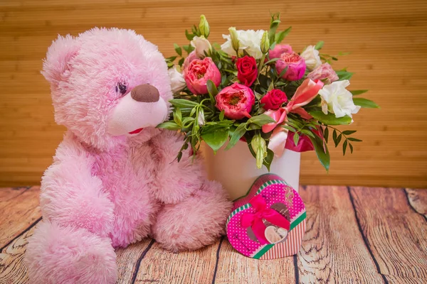 a bouquet of beautiful flowers, a toy bear and a gift
