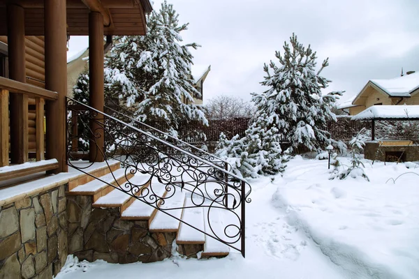 Tahta evin arka girişi tuğla merdiven ve metal parmaklıklar. Barbekü alanı olan Karlı Bahçe.
