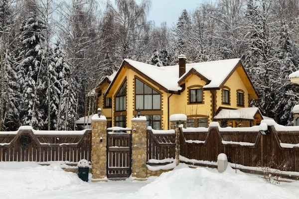 Modern mimari konsepti. Ormandaki karlı kır evi. Sarı tuğlalı lüks evi olan kış manzarası. 