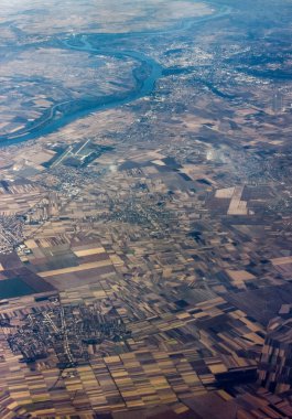Dolaşan nehir, tarlalar ve Karadağ üzerinde uçan konut alanının uçak penceresinden görüntüsü. Havadan bakış açısı. Bir uçak penceresinden manzaranın havadan görüntüsü.