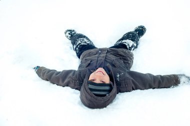 Mutlu bir şekilde kar arkasında yatan çocuk