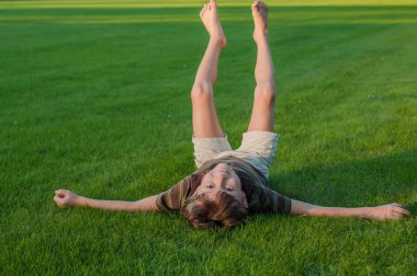Neşeli çocuk ayakları kaldırdı çim üzerinde yalan
