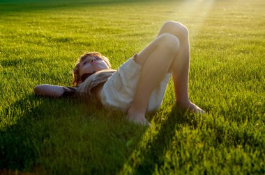 Dalgın küçük çocuk bir çim üzerinde yalan