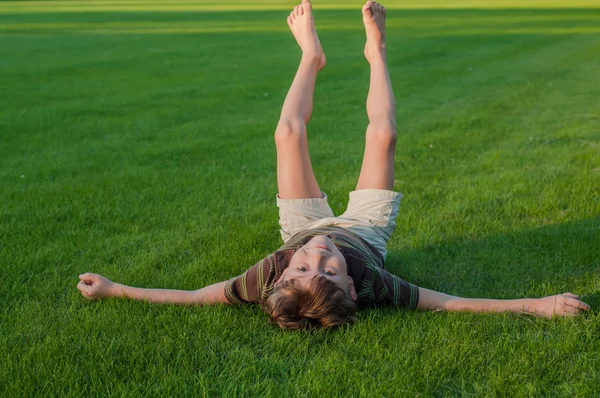 Neşeli çocuk ayakları kaldırdı çim üzerinde yalan