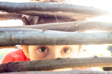 Frightened boy looks at the fence slit clipart