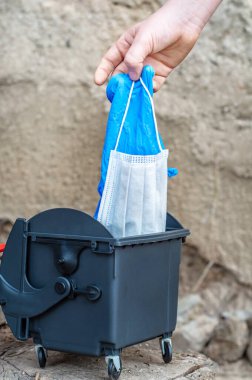 Kullanılmış plastik eldivenler ve koruyucu bir maskeyi çöpe atar. Coronavirus covid-19 salgını sona erdi. Atık geri dönüşümü. Çevrenin küresel kirliliği.