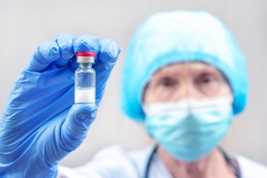 Doktor, hemşire, bilim adamı ellerinde enjeksiyon şişesi olan mavi eldivenleri teslim etti. Grip, kızamık, koronavirüs, kovid 19 aşı hastalığı. Bağışıklık kazandıran bebek, yetişkin. Aşılama. İlaç, aşı, uyuşturucu konsepti. Sağlık