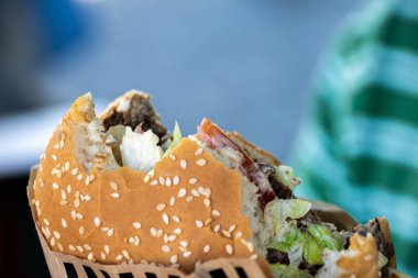 Büyük, sulu bir hamburger, ısırılarak koparılmış. Yakın plan fotoğraflar..