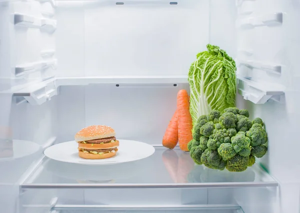 Una Hamburguesa Plato Verduras Frescas Uno Frente Otro Refrigerador Vacío — Foto de Stock