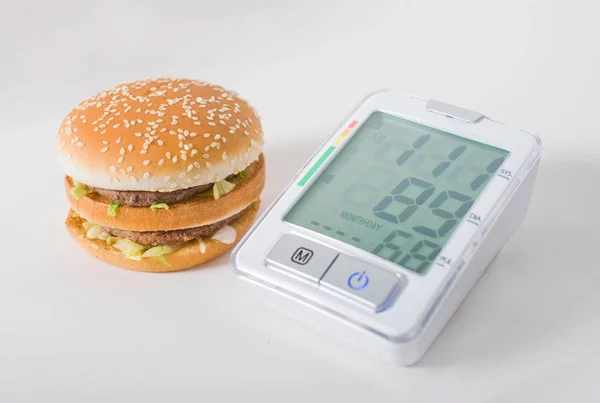 Hamburger ve basınç göstergesi beyaz arka planda. Abur cuburların sağlık etkileri
