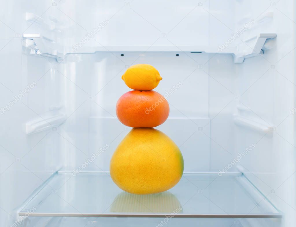 Pomelo, grapefruit, orange and lemon lie on a shelf in the refrigerator