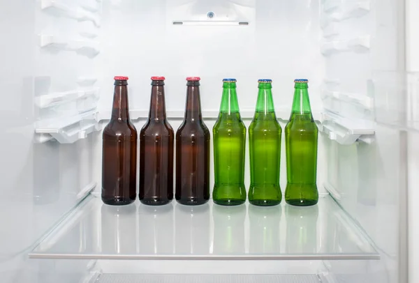 冷蔵庫の棚に緑と茶色のガラスのビールボトルが立っている — ストック写真