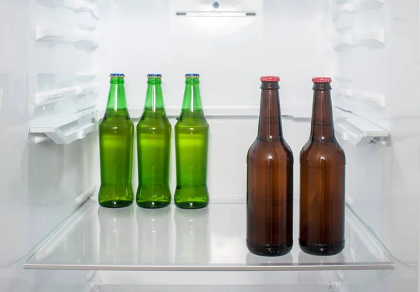 冷蔵庫の棚に緑と茶色のガラスのビールボトルが立っている — ストック写真