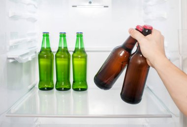 Bir adamın eli buzdolabından iki şişe bira çıkarır. yakın plan
