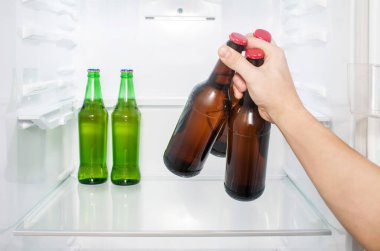 Bir adamın eli buzdolabından üç şişe bira çıkarır. yakın plan