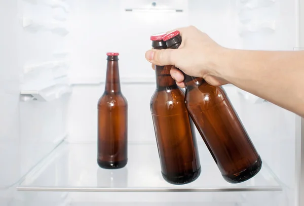 Bir adamın eli buzdolabından iki şişe bira çıkarır. yakın plan