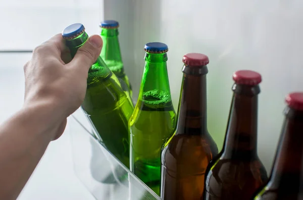 男性の手は冷蔵庫のドアからビールのボトルを取ります — ストック写真