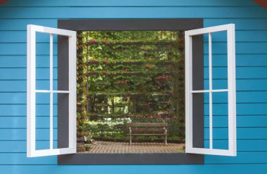 Bir sandalyede bir çiçek bahçesi içinde beyaz penceresi açılır