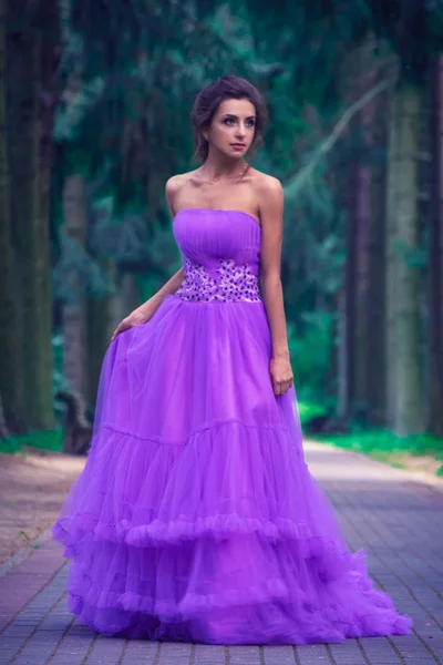 Красивая девушка в фиолетовом платье среди в саду — стоковое фото