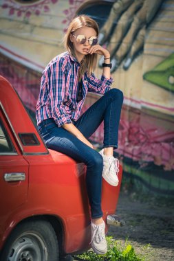 Genç çekici model retro arabanın yakınında oturuyor