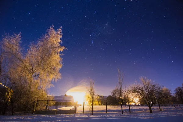 Obloha plná hvězd nad zasněženou zimní vesnice — Stock fotografie