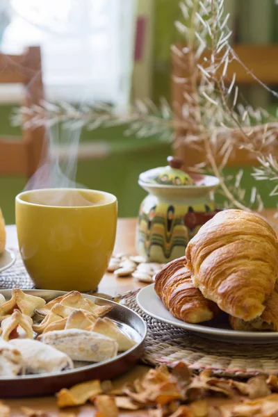 Svart te i gul mugg med bullar, croissanter och hembakade kakor — Stockfoto