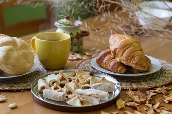 Svart te i gul mugg med bullar, croissanter och hembakade kakor — Stockfoto