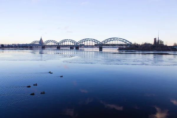 Günbatımı ışık köprüsü ve Riga Nehri üzerinde