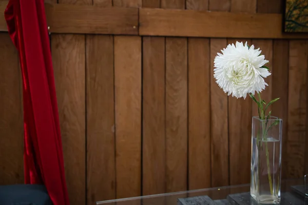 Beyaz ahşap arka plan üzerinde cam vazoda çiçek