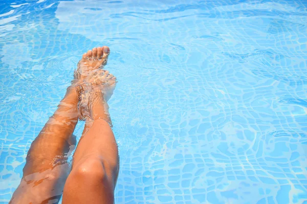 Vrouw spatten voeten in het zwembad — Stockfoto