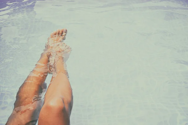 Vrouw spatten voeten in het zwembad — Stockfoto