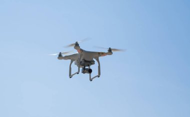 Kentsel binaların zemin üzerine şehir üzerinde parlak mavi gökyüzünde Quadrocopter insansız kamera hovers. Modern teknoloji fotoğraf ve video çekim kuşbakışı.