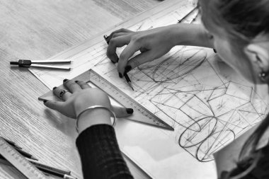 Kız mimar bir plan, tasarım, geometrik şekiller kalem tarafından büyük Ofis Masası, kağıt üzerine çizer.