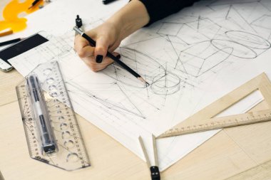 Kız mimar bir plan, tasarım, geometrik şekiller kalem tarafından büyük Ofis Masası, kağıt üzerine çizer.