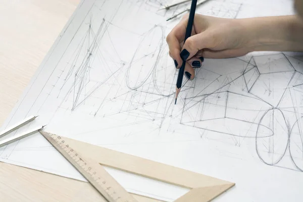 Dziewczyna architekt rysuje plan, projekt, geometryczne kształty ołówkiem na dużym arkuszu papieru na biurku. — Zdjęcie stockowe