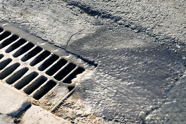 L'acqua scorre attraverso il tombino in una soleggiata giornata primaverile — Foto Stock