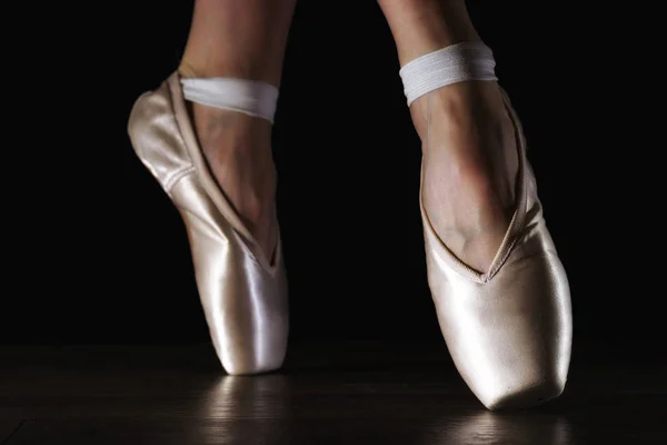 Close-up classic ballerina's legs in pointes on the black floor — Stock Photo, Image