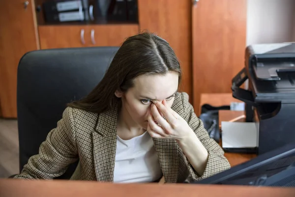 Красивая усталая деловая женщина и массирует нос во время работы в офисе — стоковое фото